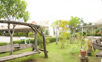 a wooden swing hanging from a tree in a lush green yard , surrounded by grass and trees at Saraburi Garden Resort