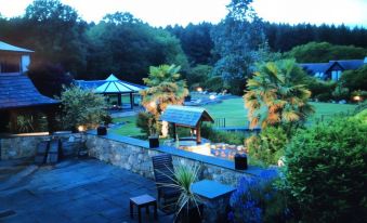 a beautiful garden with stone walls , palm trees , and benches , illuminated by warm lights at night at Hustyns Resort Cornwall