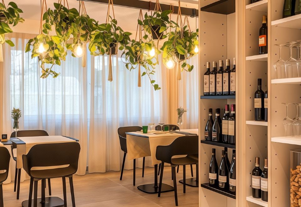 a restaurant with a dining table , chairs , and wine bottles displayed on shelves , under hanging greenery at The Green Park Hotel