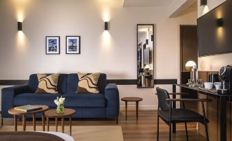 a modern living room with a blue couch , wooden chairs , and small tables , along with a mirror on the wall at Hôtel du Port
