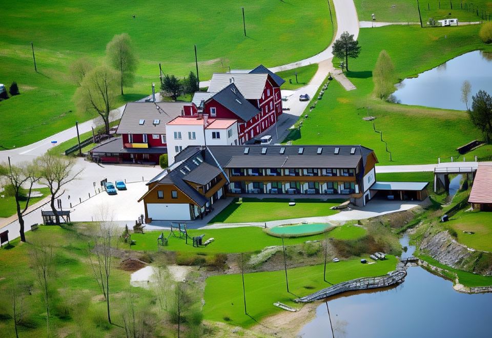 an aerial view of a golf course with a large building in the background , surrounded by green grass and trees at Hotel Albatros