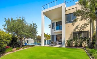 a large white house surrounded by a lush green lawn , with a swimming pool in the background at Sand Dunes Resort