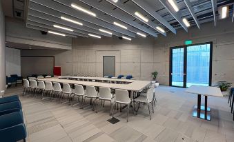 a long conference room with white chairs arranged in rows and a glass door at the end at Concept Hotel by Coaf