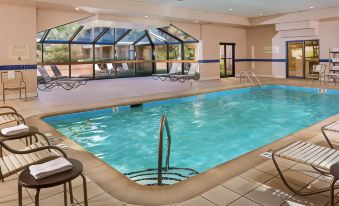 a large indoor swimming pool with a curved edge and glass walls , surrounded by lounge chairs at Courtyard Baltimore Hunt Valley
