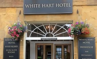the entrance of the white hart hotel , a yellow building with a black door and window arrangement at The White Hart Hotel