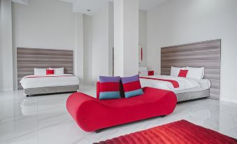 a modern bedroom with two beds , each having a red couch and pillows , set against white walls at RedDoorz Syariah @ Jalan Dieng