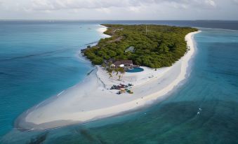 aerial view of a sandy beach with a small island in the distance , surrounded by water at Hondaafushi Island Resort