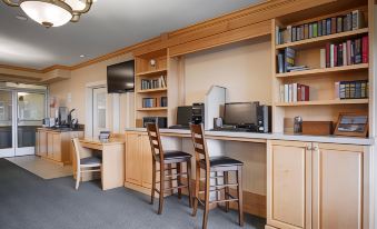 a well - organized study area with wooden shelves , desks , and chairs , as well as a television mounted on the wall at Lighthouse Suites Inn