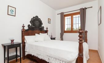 a white bedroom with a wooden bed , curtains , and a window , along with some decorative elements on the headboard at Matet