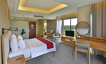 a modern hotel room with a large bed , desk , and window , all decorated in white and red at FamVida Hotel Lubuklinggau Powered by Archipelago