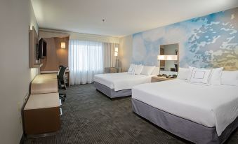 a modern hotel room with two beds , a desk , and a window , decorated with white bedding and blue clouds wallpaper at Courtyard Boston Raynham