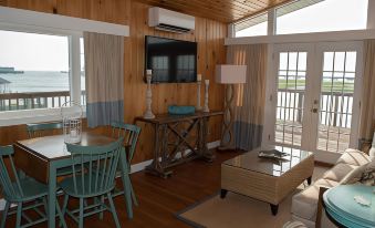 a living room with a wooden wall , blue chairs , and a flat screen tv mounted on the wall at Key West Cottages
