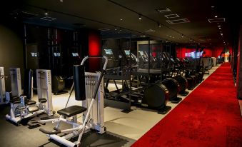 a gym with various exercise equipment , including treadmills and stationary bikes , in a black and red color scheme at Hotel Metropolitan Akita