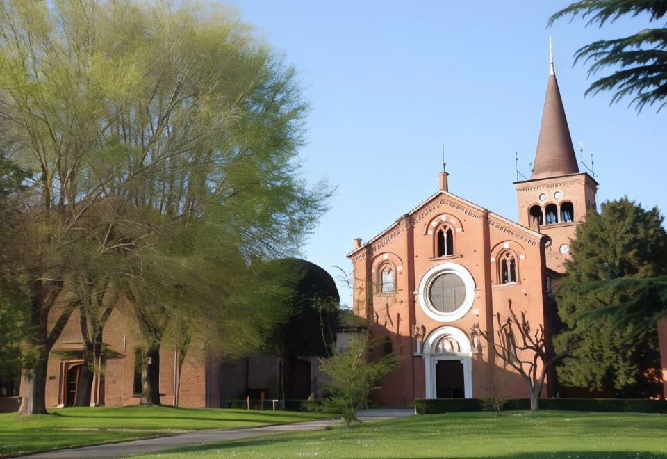 a large red brick church with a tall steeple , surrounded by green grass and trees at Hotel Majestic