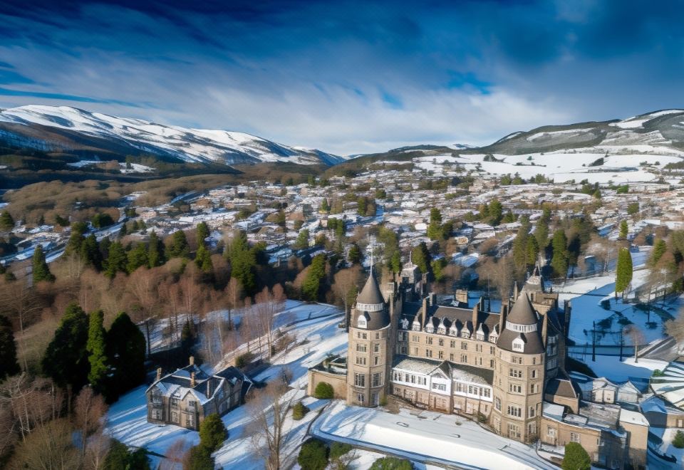 a snow - covered village with a castle - like building in the center , surrounded by snow - covered fields and mountains at The Atholl Palace