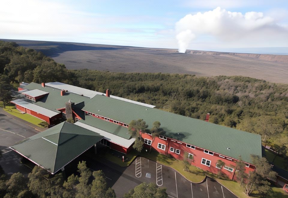 an aerial view of a large building with a red roof and green roof , surrounded by trees and mountains at Volcano House