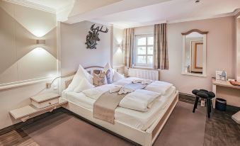 a large bed with white linens and a headboard is in a room with beige walls at Hotel Restaurant der Engel, Sasbachwalden