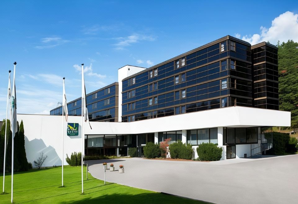 a large white building with a green flag on the front , surrounded by trees and grass at Quality Hotel Entry