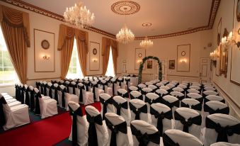 a large room with rows of white chairs set up for a wedding or banquet at Melville Castle Hotel