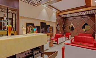 a modern lounge area with red chairs , white tables , and a bar , surrounded by wooden panels and a large mirror at The Fern Residency Aurangabad