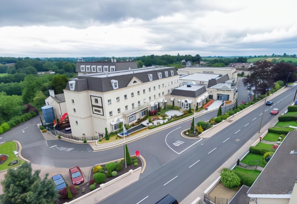 a large hotel building surrounded by grass and trees , with a parking lot in front of it at Hillgrove Hotel, Leisure & Spa