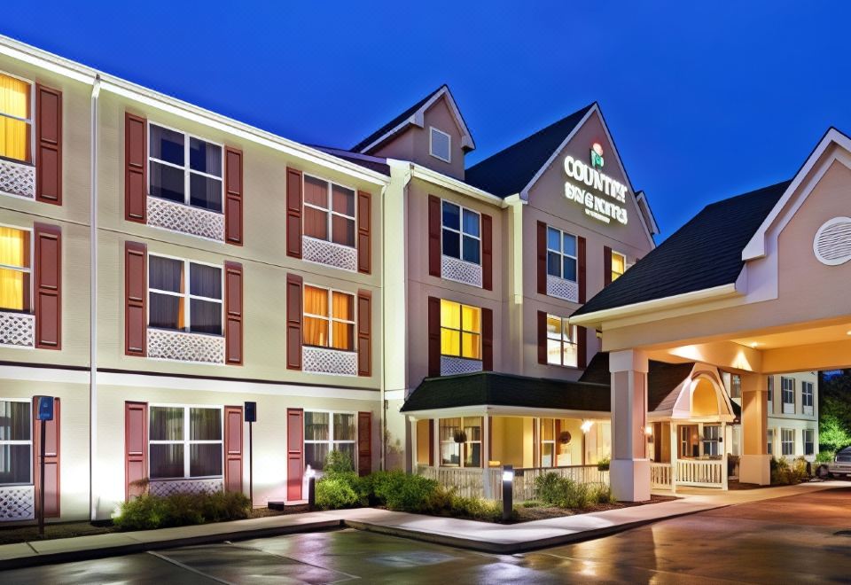 a large hotel with multiple doors and windows , illuminated by lights at night , is situated in a parking lot at Country Inn & Suites by Radisson, Harrisburg Northeast - Hershey