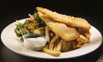 a white plate with a variety of food items , including fish , french fries , and a salad at Nightcap at the Charles Hotel