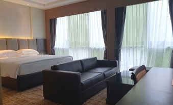 a modern hotel room with a black leather couch , wooden desk , and large window curtains at KSL Hot Spring Resort