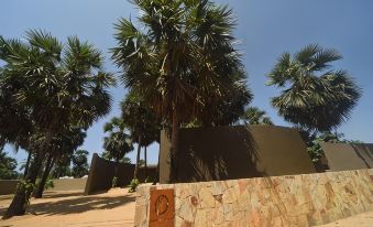a tall palm tree in front of a building , with a stone wall on the side at Karpaha Sands