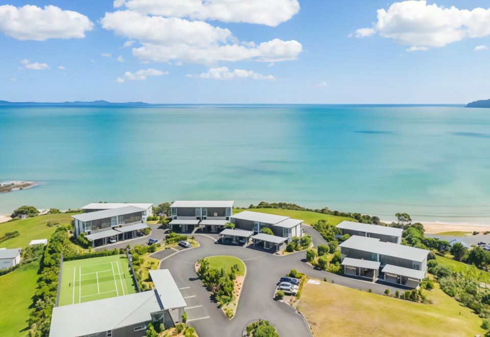 a bird 's eye view of a beachfront property with houses and a tennis court at Doubtless Bay Villas