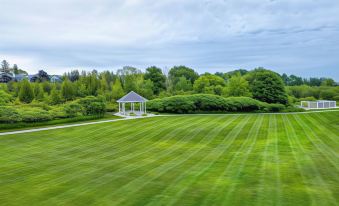 a grassy field with a gazebo in the background , surrounded by trees and bushes at Newport Resort