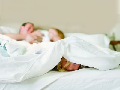 a woman and a child are sleeping on a bed with a white sheet covering her face at Country Inn & Suites by Radisson, Watertown, SD