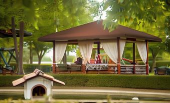 a wooden gazebo surrounded by lush greenery , with a couple sitting on a bench under it at Hotel Bellevue