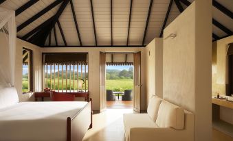a bedroom with a bed , couch , and sliding glass doors leading to an outdoor patio at Jetwing Kaduruketha