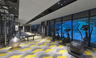 a modern gym with a yellow and black geometric patterned floor , multiple exercise equipment , and large windows at Aloft Perth