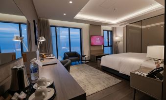 a modern hotel room with a king - sized bed , a flat - screen tv , a desk , and a chair at Swiss-Belboutique Bneid Al Gar Kuwait
