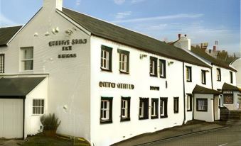 "a white building with black trim and the words "" coffee - cottage inn "" on it , situated in a rural area" at Queens Head Inn