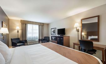 a hotel room with a king - sized bed , a flat - screen tv , a desk , and a chair at Quality Inn & Suites Newberry