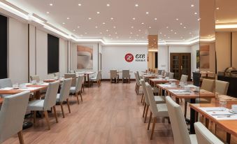 a dining room with wooden tables and chairs , white walls , and a red logo on the wall at Exe Salamanca