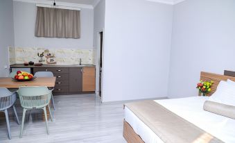 a modern , minimalist bedroom with white walls and wooden floors , featuring a bed , a dining table , and a kitchen area at Garden Inn Resort Sevan