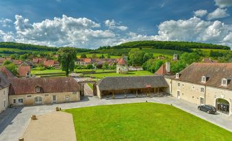 a picturesque village with a large grassy field in the center , surrounded by several buildings at Hotel Golf Chateau de Chailly