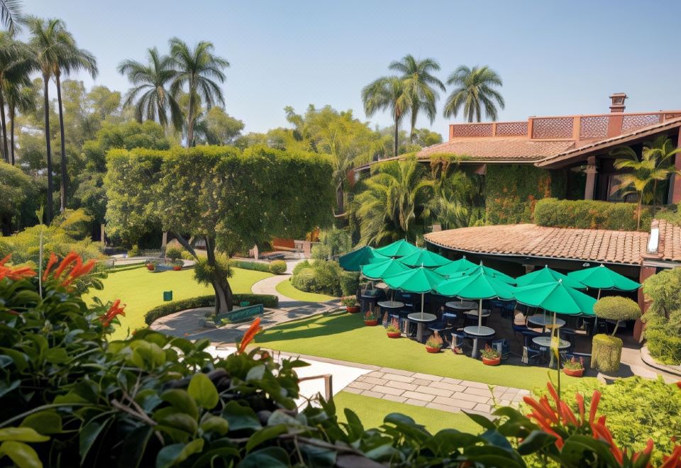 a courtyard surrounded by lush greenery , with several umbrellas providing shade for people sitting at tables at Las Mañanitas