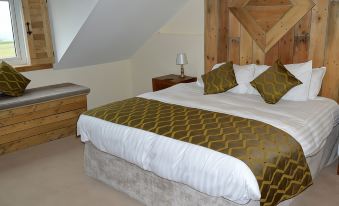 a large bed with a white comforter and gold throw blanket is in a room with wooden walls at The Anchor Inn