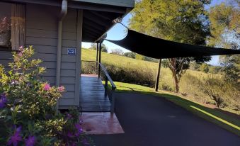a paved walkway leading to a house , with a covered porch and a black canopy overhead at Alstonville Country Cottages