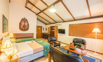 a modern hotel room with wooden beams , white walls , and a blue bed , as well as black leather chairs and a table at Madang Resort
