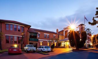 a brick building with a large sign on the side , surrounded by a parking lot filled with cars at Mercure Maitland Monte Pio