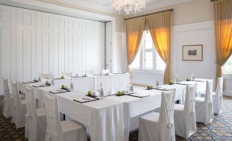 a conference room set up for a meeting , with tables and chairs arranged in a semicircle at Victoria Bed & Breakfast