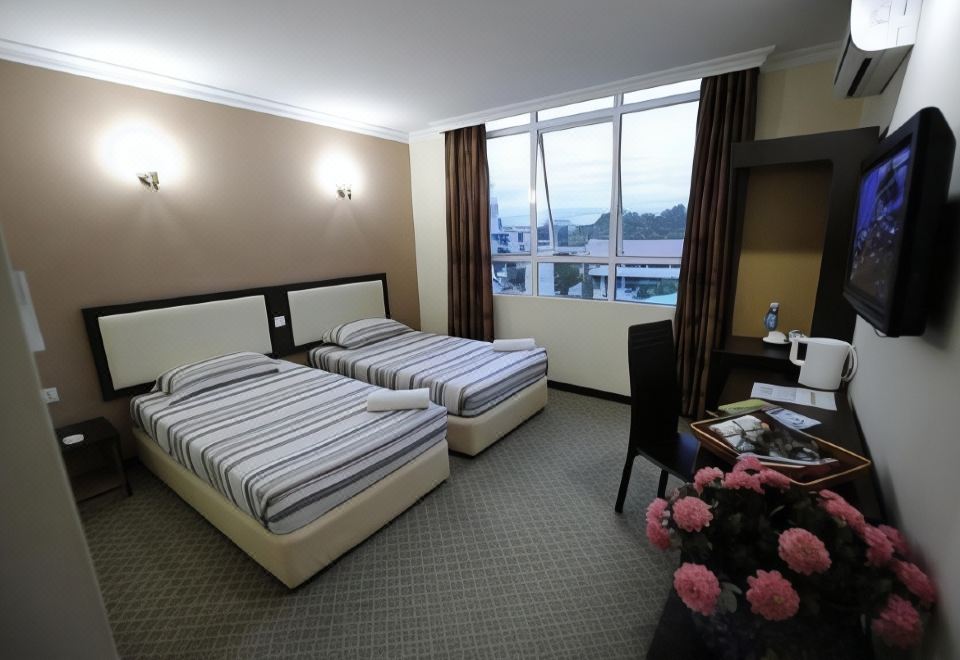 There are two beds in the bedroom, positioned next to each other, with a large window on the side at Golden Hotel
