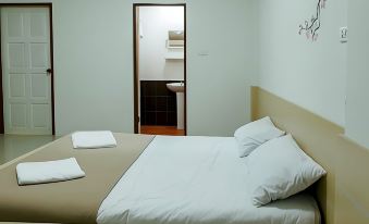 a bed with white sheets and pillows is in a room with a door open at Cheaper Room