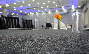 a conference room with a gray carpet , white chairs , and blue lights , as well as a vase of flowers on the table at The Crown